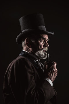 Pipe smoking vintage victorian man with black hat and gray hair