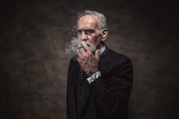 Cigar smoking characteristic senior business man with gray hair