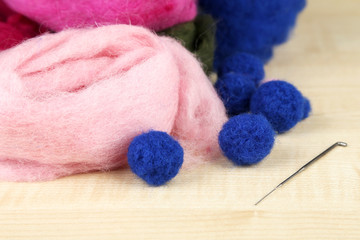 Wool for felting with needle on wooden background