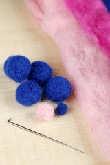 Wool for felting with needle on wooden background