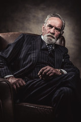 Obraz na płótnie Canvas In chair sitting characteristic senior business man. Smoking cig