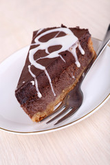 Piece of chocolate cake on saucer on wooden background