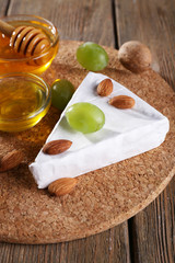 Brie cheese, honey in glass bowl, nuts and grapes