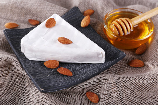 Brie cheese, honey in glass bowl and nuts