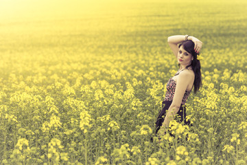 Beautiful woman in meadow of yellow flowers with arm up