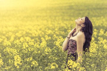 Beautiful woman in meadow of yellow flowers with head up