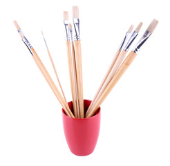 Paint brushes in red mug isolated on white