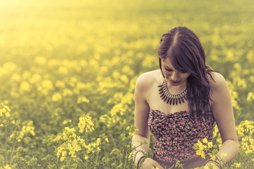 Beautiful woman in meadow of yellow flowers looking down