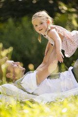 Vater liegt auf Rücken hält Tochter im Luft im Garten
