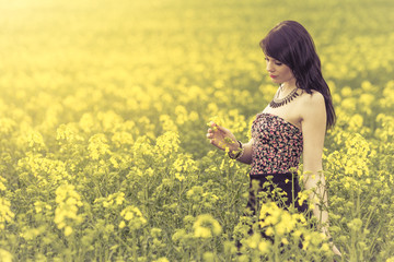 Beautiful woman in meadow of yellow flowers recognizing flower