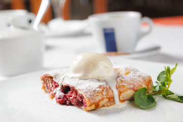 Cherry strudel with ice cream and mint leaf.