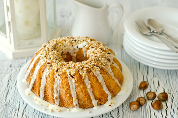 Glazed cake with hazelnuts on white background