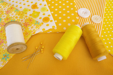 Accessories for sewing: threads, fabric, buttons in yellow-white