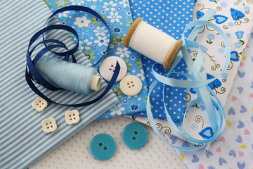Accessories for sewing: threads, fabric, buttons in blue-white c
