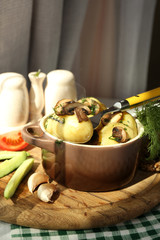 Young boiled potatoes in pan with vegetables on table in