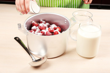 Cooking delicious strawberry jam in kitchen