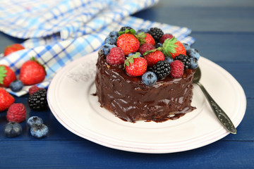 Tasty chocolate cake with different berries, on wooden table