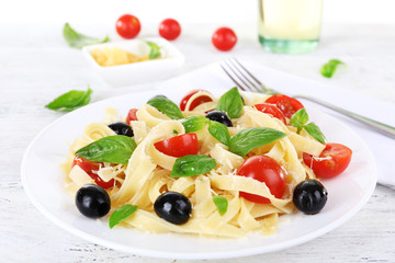 Spaghetti with tomatoes, olives and basil leaves