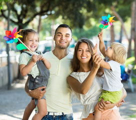 Young parents with children playing windmills