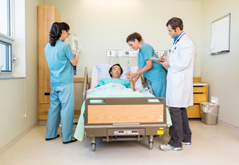 Nurses And Doctor Examining Patient In Hospital