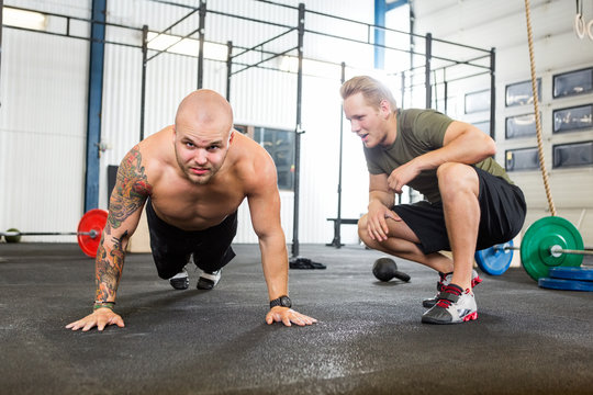 Trainer Assisting Man In Doing Pushups