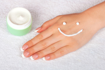 Cream smile face on female hand with french manicure 