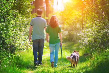 Young couple holding hands and walking with their dog