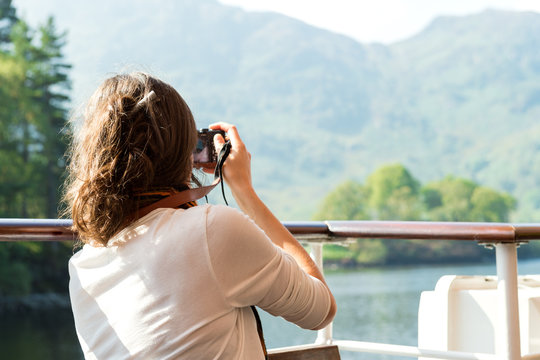 Female enjoying boat ride, taking photos, Scottish Highlands