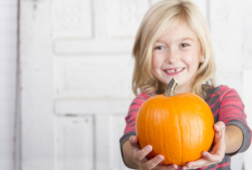 child holding a small pumpkin