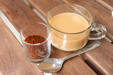 cup of milk coffee and coffee powder on wooden table.
