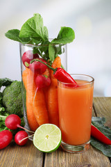 Fresh carrot juice with vegetables on wooden table