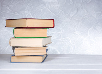 Books on wooden table on light background