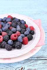 Iced berries on plate, on color wooden background