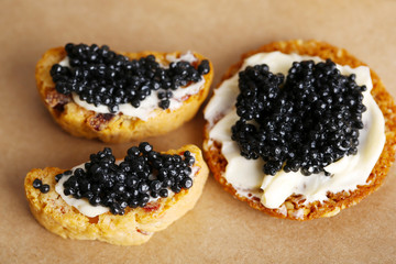 Slices of bread with butter and black caviar on paper