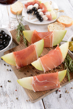 Delicious melon with prosciutto on table close-up