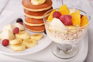 Pancake with fruits and muesli on plate on table close up