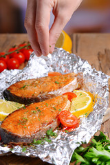 Tasty baked fish in foil on table close-up