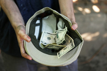 Homeless beggar money on his hat