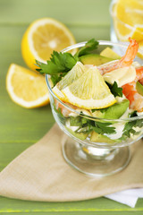 Tasty salad with shrimps and avocado, on wooden background