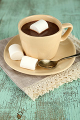 Hot chocolate with marshmallows in mug, on wooden background