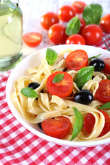 Spaghetti with tomatoes, olives and basil leaves