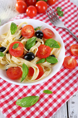 Spaghetti with tomatoes, olives and basil leaves