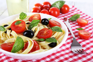 Spaghetti with tomatoes, olives and basil leaves