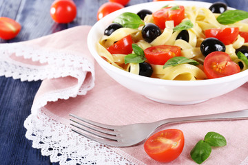 Spaghetti with tomatoes, olives and basil leaves