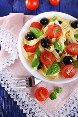 Spaghetti with tomatoes, olives and basil leaves