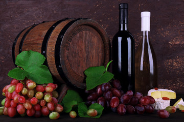 Wine in bottles, Camembert and brie cheese, grapes and wooden