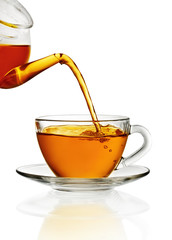 Tea pouring into glass cup isolated in white