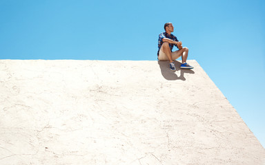 Young man sitting on a wall