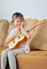 Asian little girl hold an ukulele and smiling