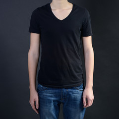 Obraz premium Young man in blank black t-shirt over dark background, teen boy